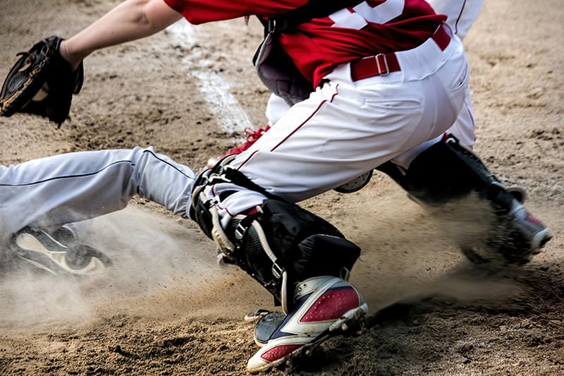 Baseball Player Sliding into Home Plate with a catcher putting a tag on.