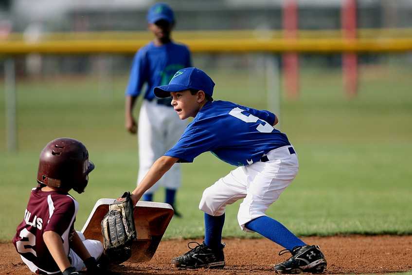 A youth player sliding into a base while being tagged out